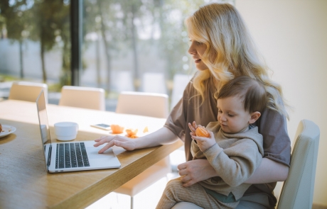 woman-carrying-her-baby-and-working-on-a-laptop-4079281